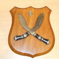 Crossed Indian Kukris with cap badge mounted on a Teak board/shield