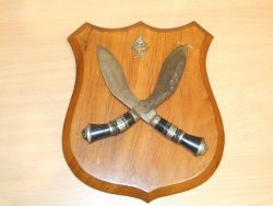 Crossed Indian Kukris with cap badge mounted on a Teak board/shield